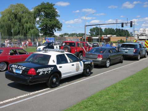 2001 Ford Crown Victoria - A police car with "POLICE" and "EMERGENCY 9-1-1" markings is seen in a line of vehicles.