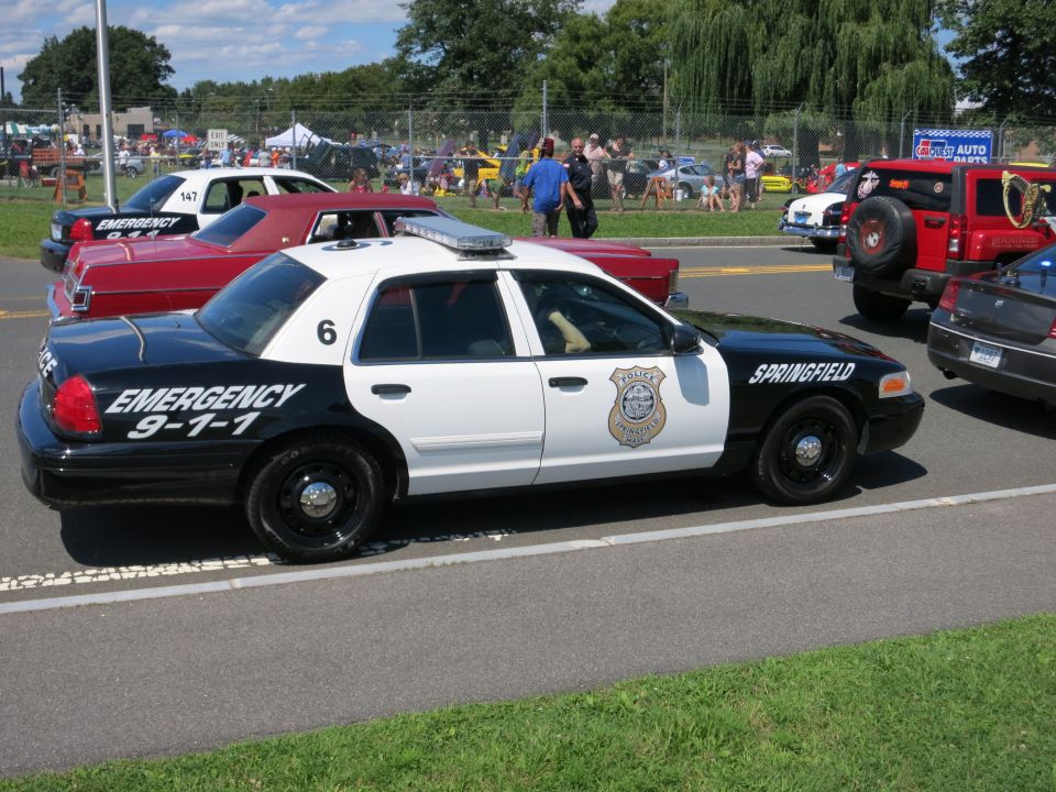 Black and white police car with "EMERGENCY 9-1-1" and "SPRINGFIELD" text, parked next to other vehicles