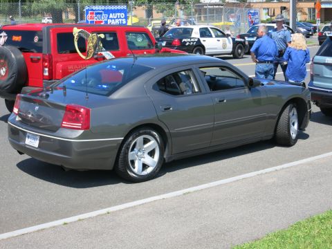 2001 Ford Crown Victoria - A gray Dodge Charger is parked on the street with police vehicles and a red Jeep in the background.