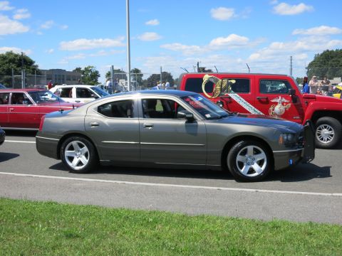 2001 Ford Crown Victoria - Side view of a gray Dodge Charger police car with a red Hummer in the background.