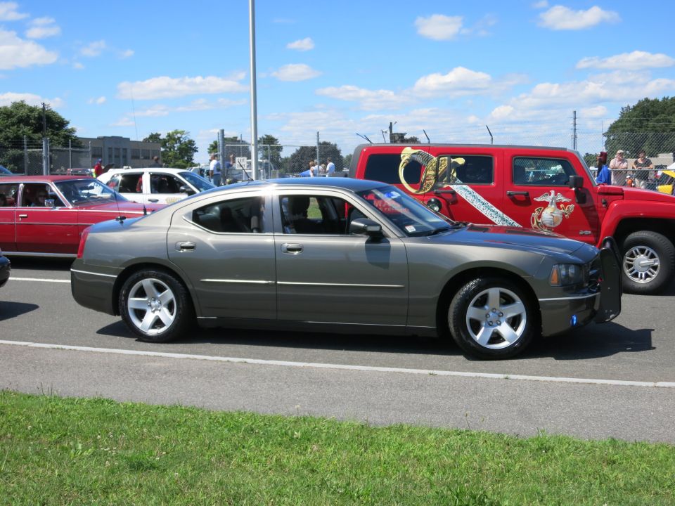 Gray Dodge Charger police car parked next to a red Hummer with Marine Corps graphics