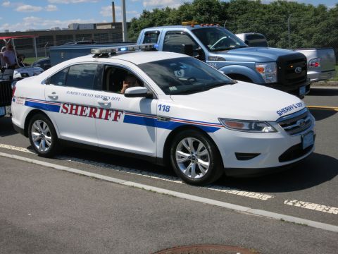 2001 Ford Crown Victoria - A white sheriff's vehicle is parked next to a blue pickup truck.