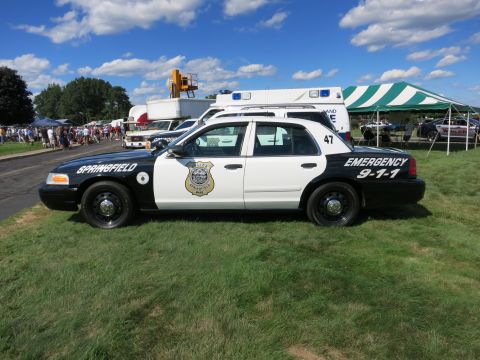 2001 Ford Crown Victoria - Side view of a black and white 2001 Ford Crown Victoria police car with "SPRINGFIELD" and "EMERGENCY 9-1-1" text.