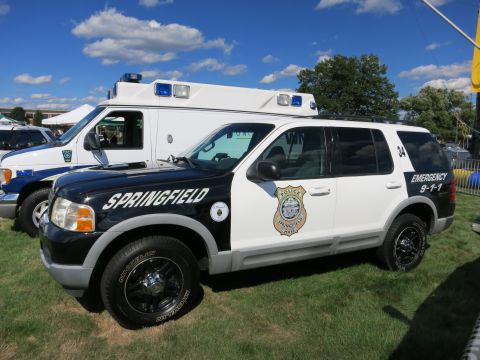 2001 Ford Crown Victoria - A police SUV is parked on grass next to an ambulance, with "SPRINGFIELD" and "EMERGENCY 9-1-1" markings visible.
