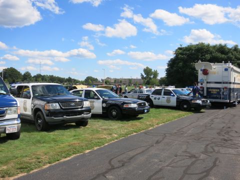 2001 Ford Crown Victoria - Several police vehicles, including a Ford Crown Victoria and a Ford Explorer, are parked in a line on a sunny day.