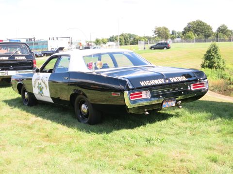 2001 Ford Crown Victoria - A black and white police car is parked on a grassy field, with another vehicle visible in the background.