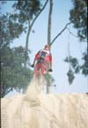 1979 Ford Bronco - A motocross rider soars through the air, leaving a trail of dust behind them against a clear blue sky.