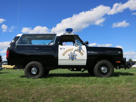 2001 Ford Crown Victoria - A side view of a black and white police SUV with a light bar on the roof.