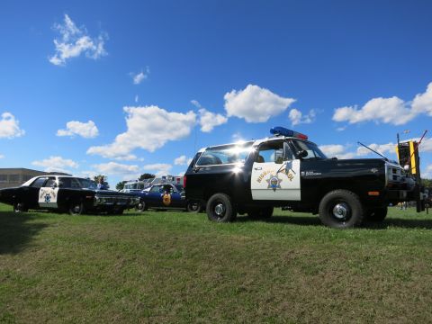 2001 Ford Crown Victoria - A black police SUV with a Highway Patrol decal and light bar is parked on a grassy field next to other police vehicles.