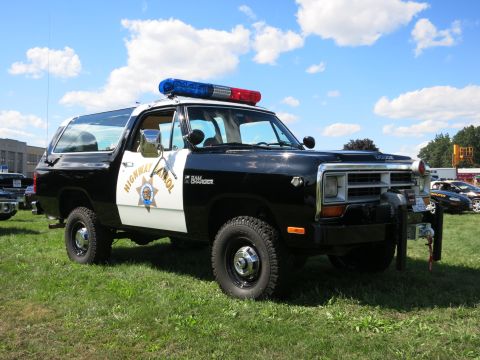 2001 Ford Crown Victoria - A vintage Dodge Ramcharger SUV is displayed on a grassy field under a blue sky with clouds.