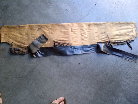 1994 Ford Bronco - A car part, possibly a trim piece, is laid out on a concrete surface with torn brown paper and black tape.