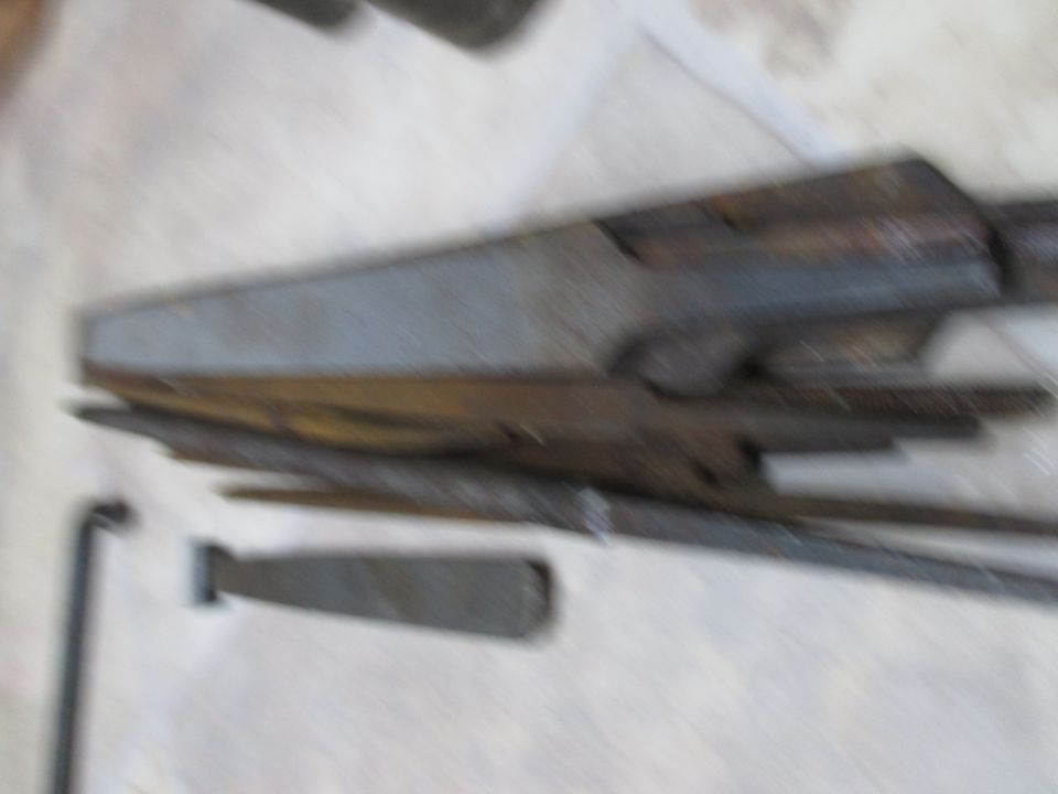 Metal car part, possibly a chassis component, with rust and wear. Tools are nearby