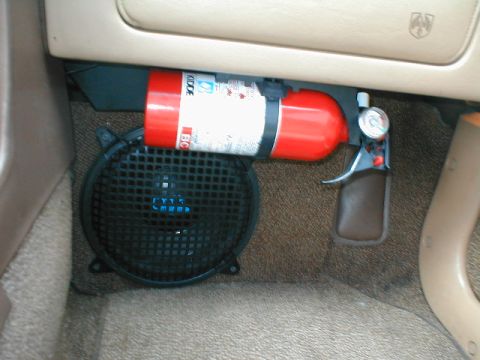 1994 Ford Crown Victoria - A red fire extinguisher is mounted under the dashboard, positioned above a black speaker grille.