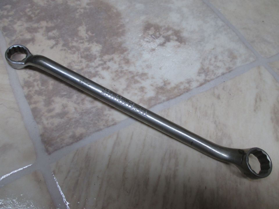 Combination wrench with text stamped on the shaft, lying on a tiled floor