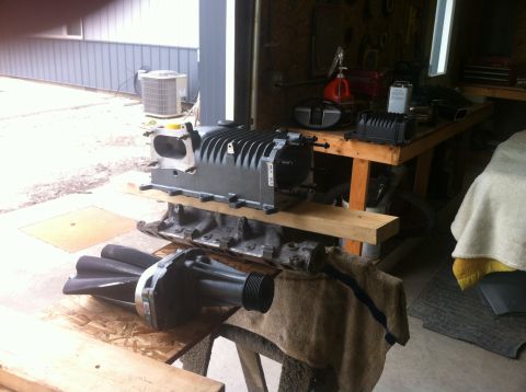 2003 Ford Crown Victoria - A supercharger and engine block are staged on sawhorses in a workshop setting.