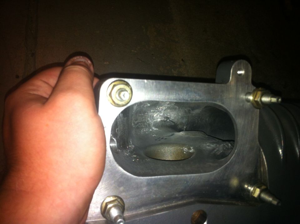 Intake manifold with a hand holding it. Supermotors.net logo visible