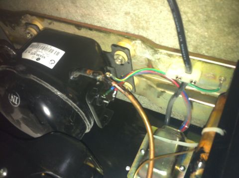 2003 Ford Crown Victoria - A close-up view of a compressor and its associated wiring, mounted on a bracket.