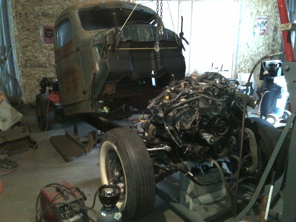 Truck chassis in garage with engine assembly and welding equipment