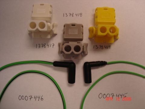 1989 BMW 3 Series - Three spark plug wire connectors in white, grey, and yellow are shown with two green spark plug wires with black boots.