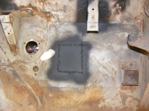 Rusty vehicle firewall with a welded square patch and a circular opening