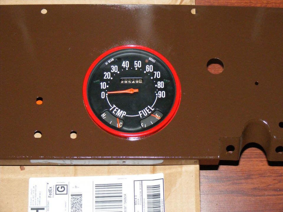 Brown painted instrument cluster panel with a red-bezeled gauge showing speed, temperature, and fuel