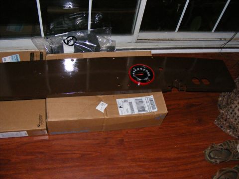 Brown dashboard section with a red-bezeled gauge and some boxes underneath