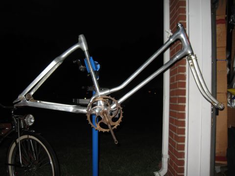 1994 Ford Bronco - Aluminum bicycle frame and fork assembly on a stand, with a partial view of a bicycle wheel.
