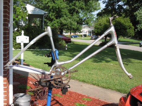 1994 Ford Bronco - A bicycle frame is mounted on a repair stand in front of a house, with a residential street in the background.