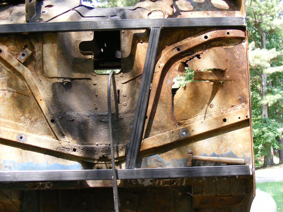 Rusted vehicle frame with metal bracing, showing significant corrosion and damage