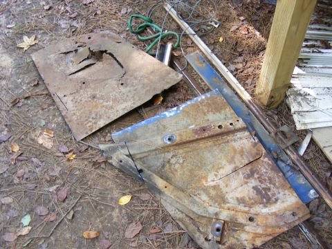 Rusted metal car door and panel pieces on the ground