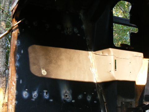 Interior of a vehicle under construction, showing metal panels and a window opening