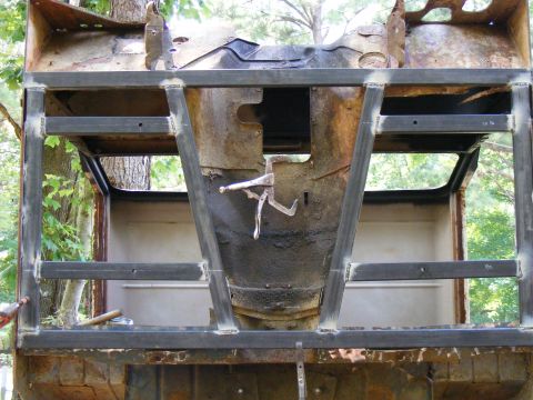 Rusted vehicle chassis with added metal frame, viewed from the front interior