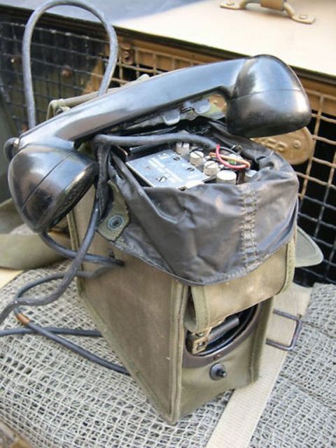 1991 Ford LTD Crown Victoria - A vintage military field telephone handset rests atop its canvas carrying case, revealing internal wiring and components.
