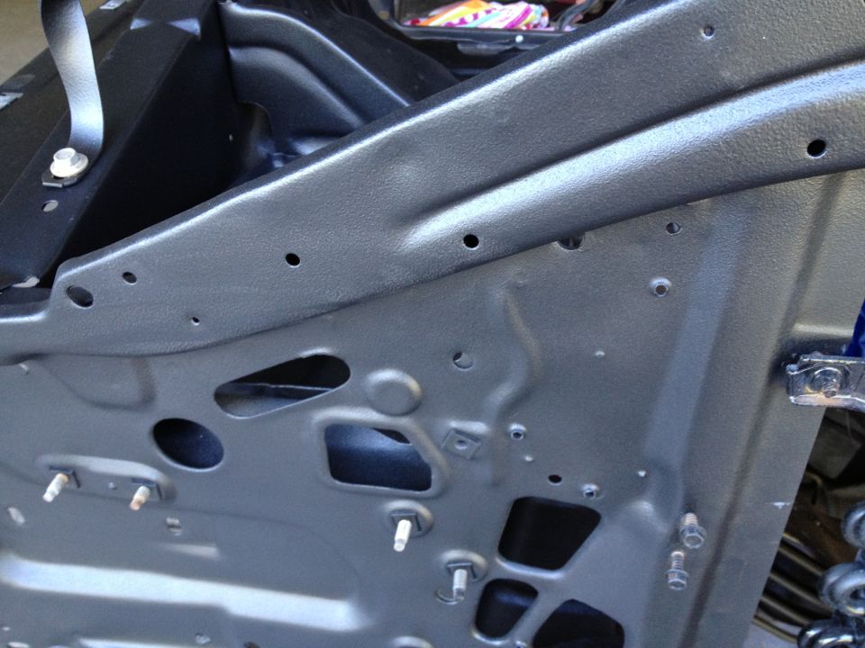 Inside of a vehicle door, showing metal bracing and mounting points. Some blue is visible in the background