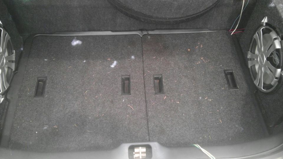 Car trunk with two subwoofers installed on the sides and carpeted floor