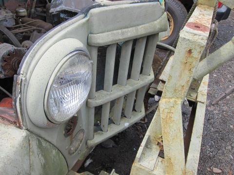 2001 Ford Crown Victoria - Close-up of a weathered Jeep grille and headlight, showing signs of age and disrepair.