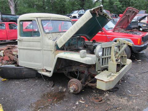 2001 Ford Crown Victoria - Willys Jeep truck in a junkyard with a red Jeep Cherokee behind it.