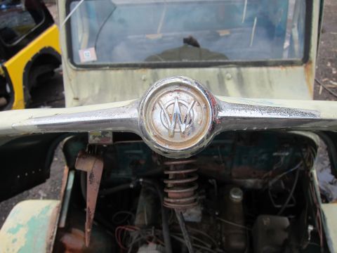 2001 Ford Crown Victoria - The chrome emblem on this old jeep features a distinctive 'W' logo, with engine components exposed underneath.