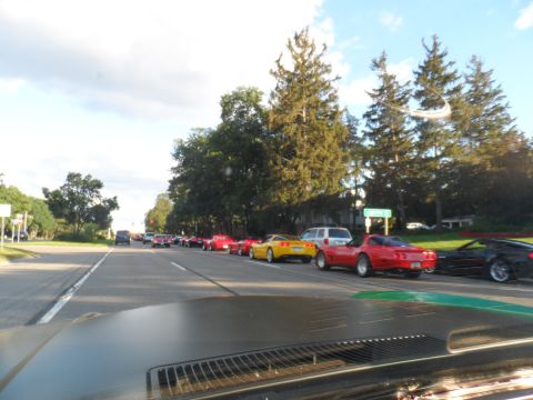 1971 Ford Ranchero - A convoy of Corvettes and other vehicles travels down a tree-lined road on a sunny day.