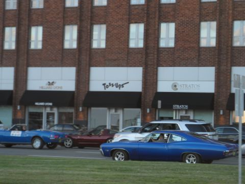 1971 Ford Ranchero - A blue 1969 coupe is seen driving on a street in front of a brick building with storefronts.