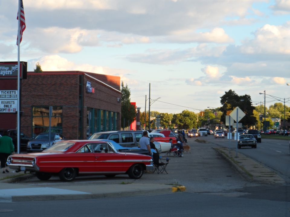 Red 1964 Ford Falcon parked on street with other cars and people