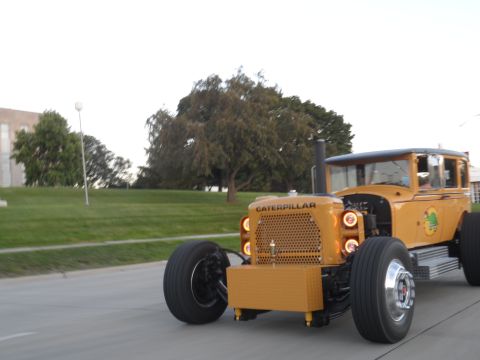 1971 Ford Ranchero - A custom yellow tractor hot rod is seen from the front as it drives down a road.