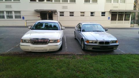 1997 BMW 3 Series - Two cars, a silver BMW 3 Series and a white Mercury Grand Marquis, are parked in front of a building.