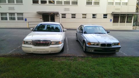 1997 BMW 3 Series - A silver 1997 BMW 3 Series is parked in front of a building, alongside a white Mercury Grand Marquis.