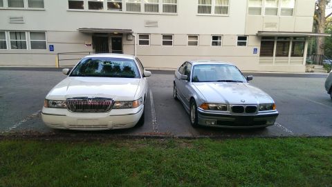 1997 BMW 3 Series - Two cars, a 1997 BMW 3 Series and a Mercury Grand Marquis, are parked in front of a building.