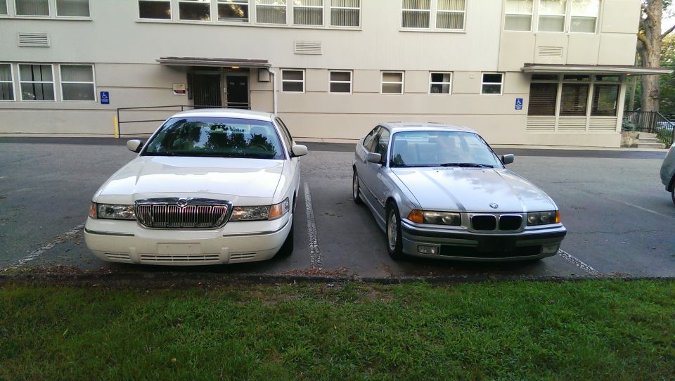 Silver 1997 BMW 3 Series parked next to a white Mercury Grand Marquis