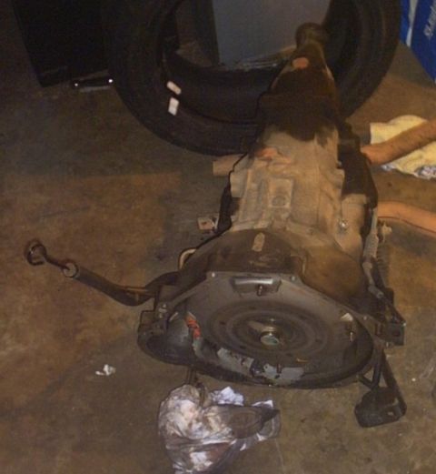1991 Ford LTD Crown Victoria - Automatic transmission removed from a vehicle, resting on a garage floor.