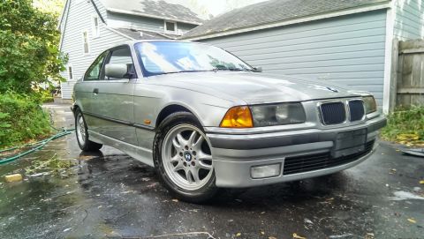 1997 BMW 3 Series - Silver 1997 BMW 3 Series coupe with a wet driveway and house in the background.