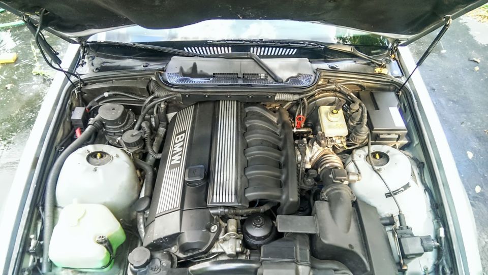 BMW engine bay with the hood open, showing the engine cover with "BMW" text