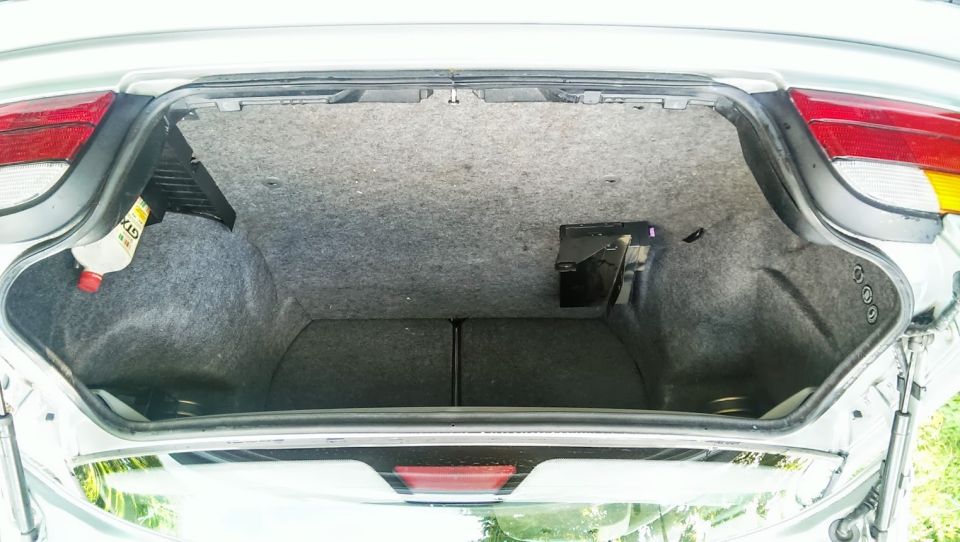 Car trunk interior with a bottle of oil and a black electronic box